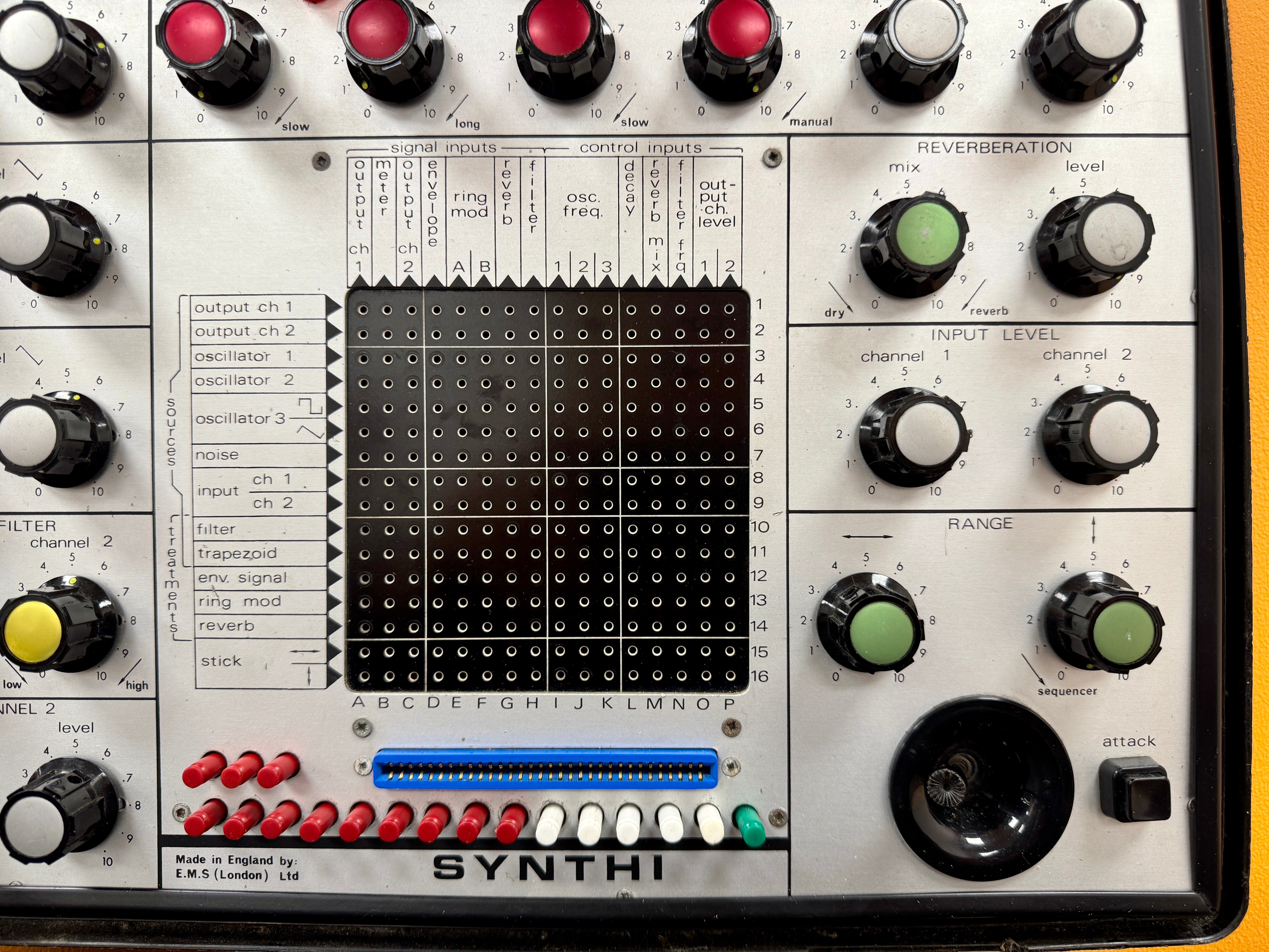 Close-up of a synthesizer with various knobs and buttons on a white background