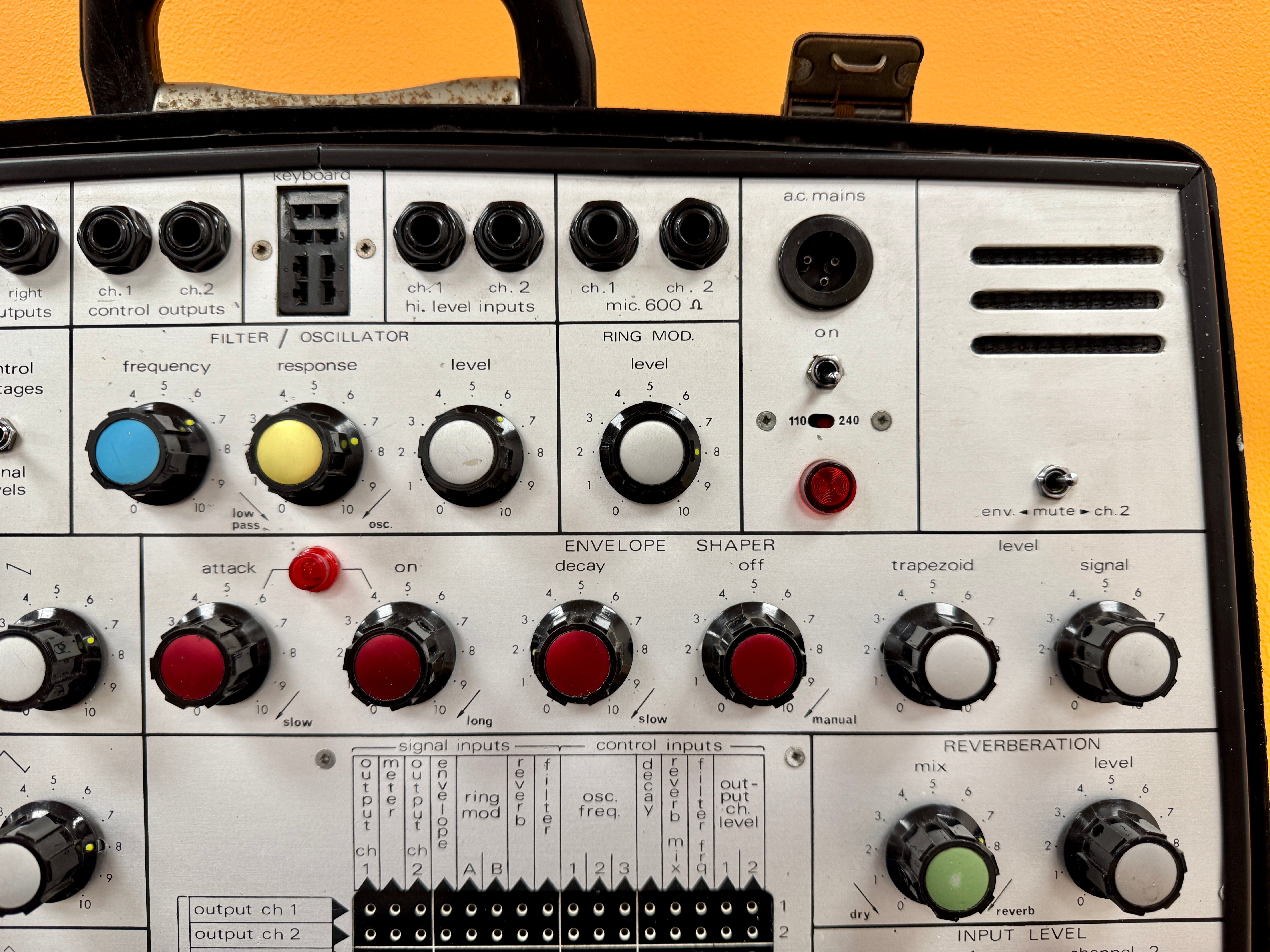 Vintage electronic equipment with control knobs and buttons on a yellow background