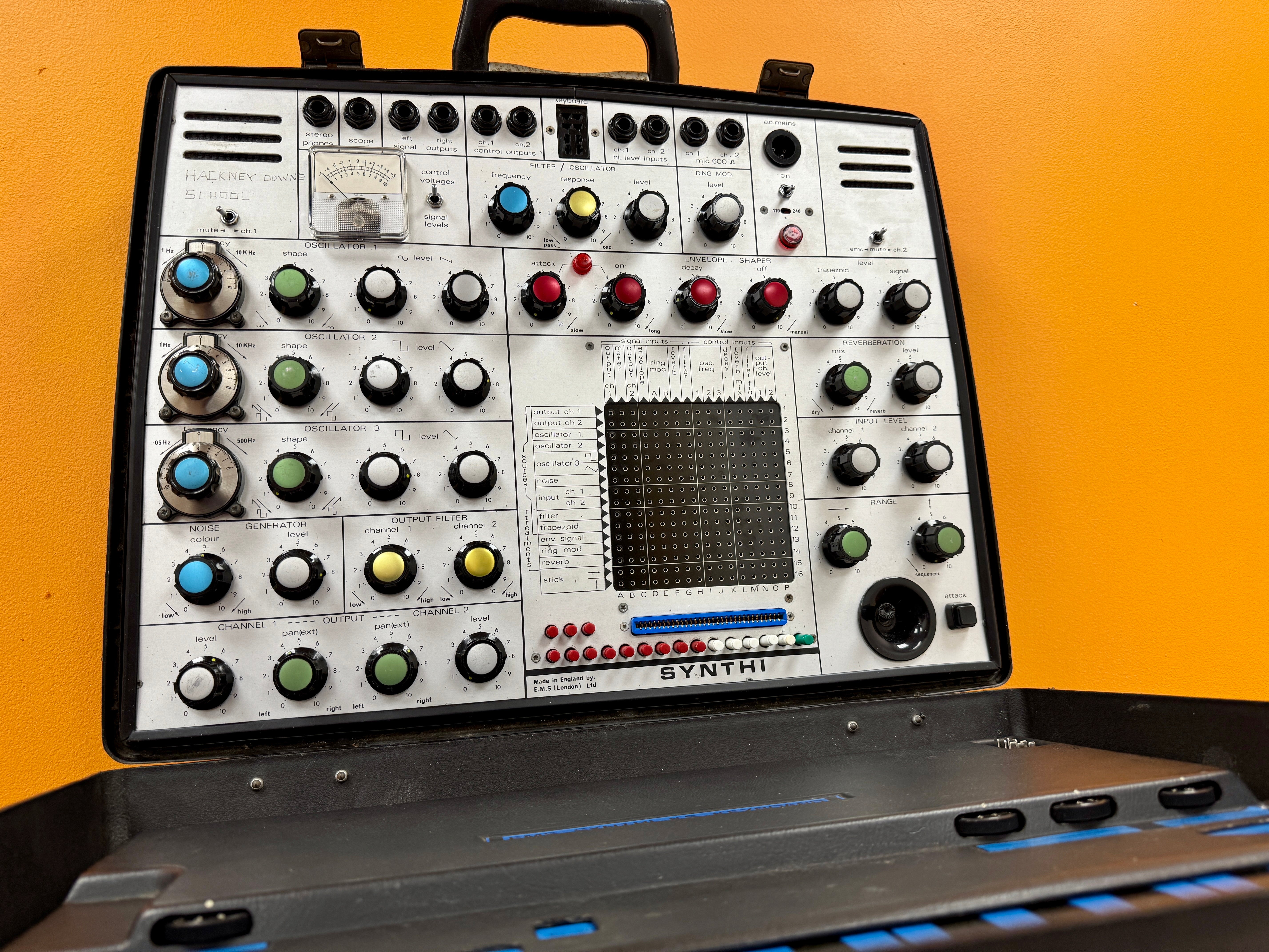 Vintage synthesizer with control panel and keyboard on a yellow background