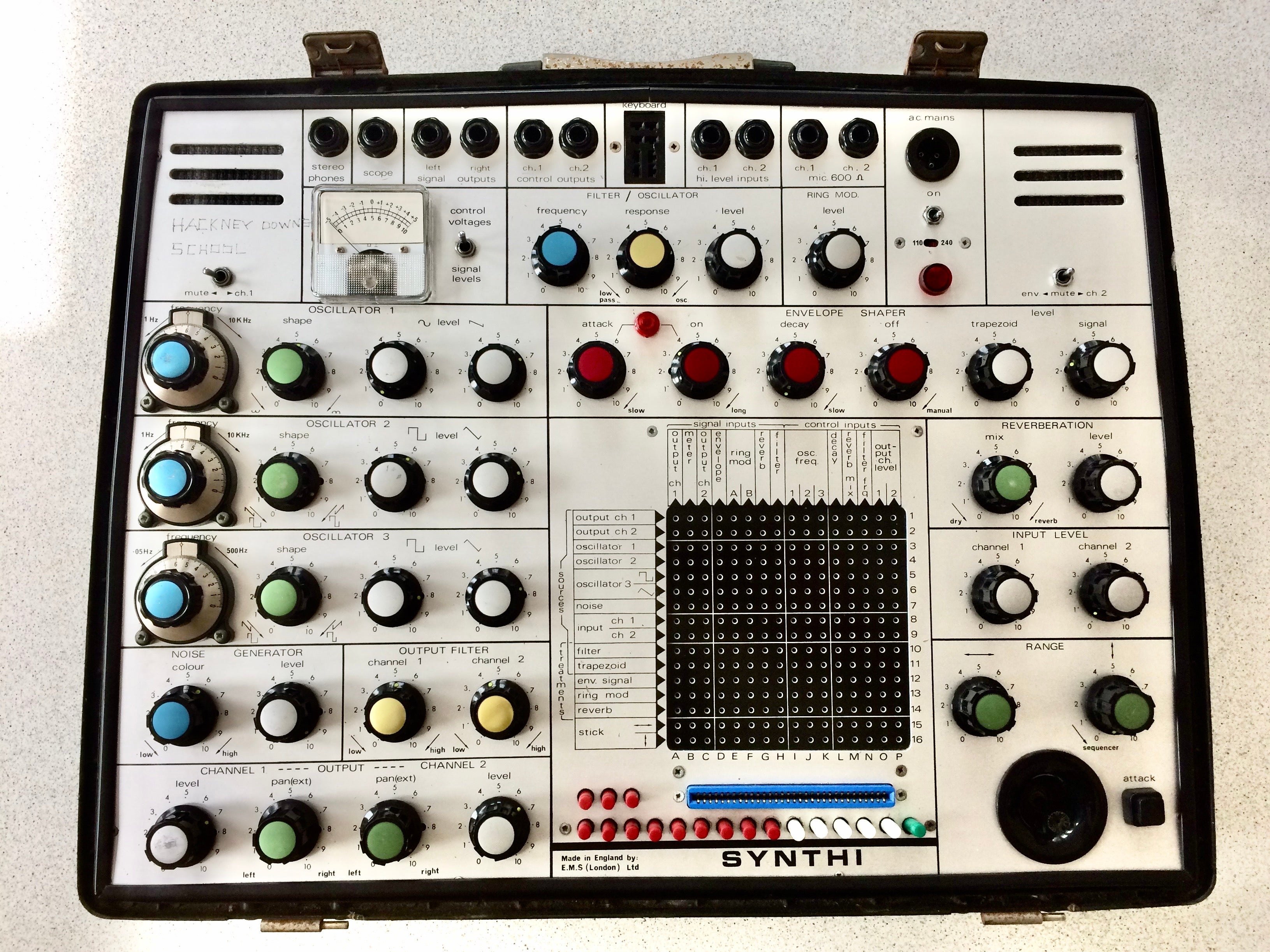 Vintage synthesizer with various knobs and buttons on a light gray background