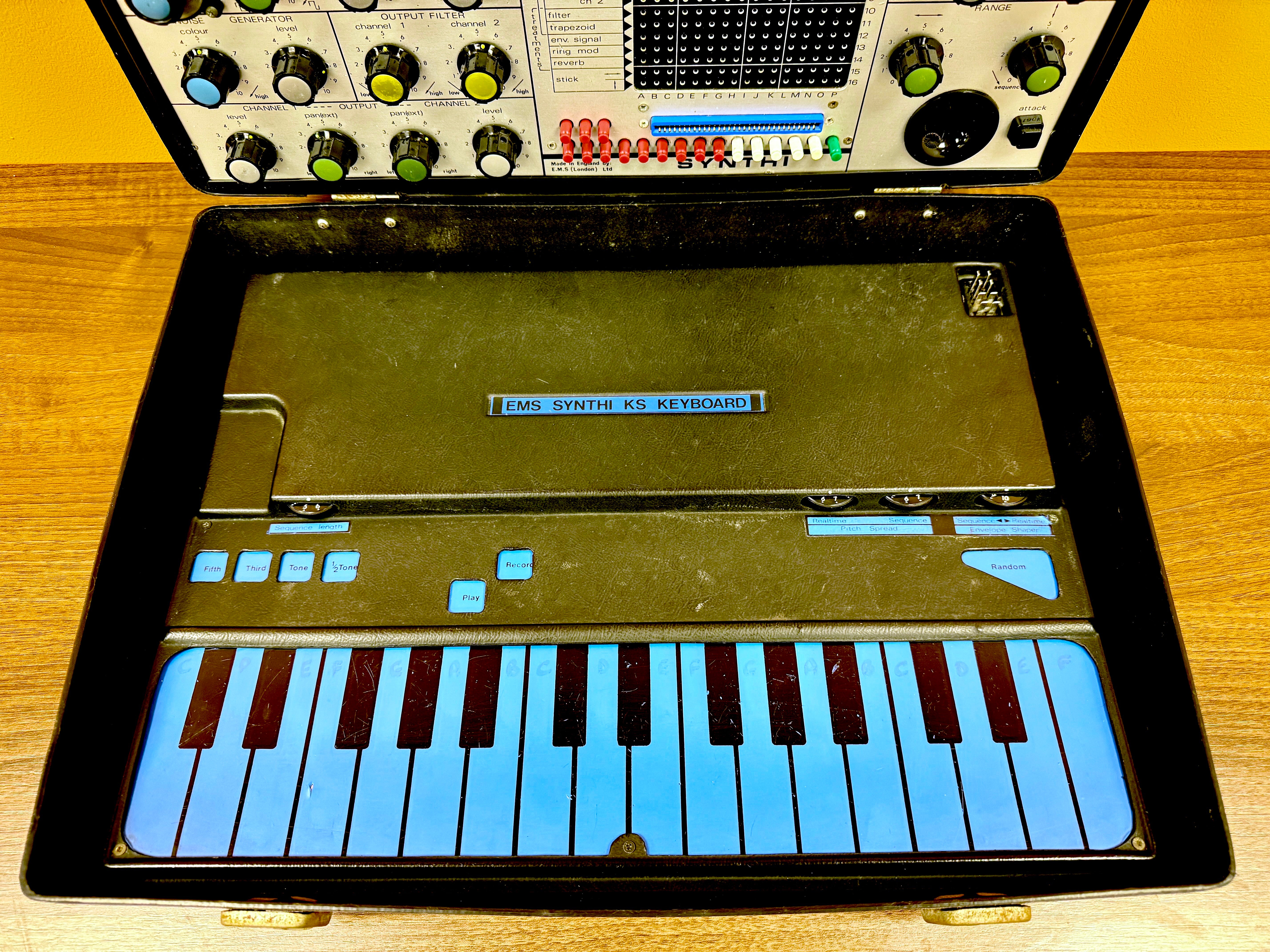 Keyboard synthesizer with blue keys on a wooden surface