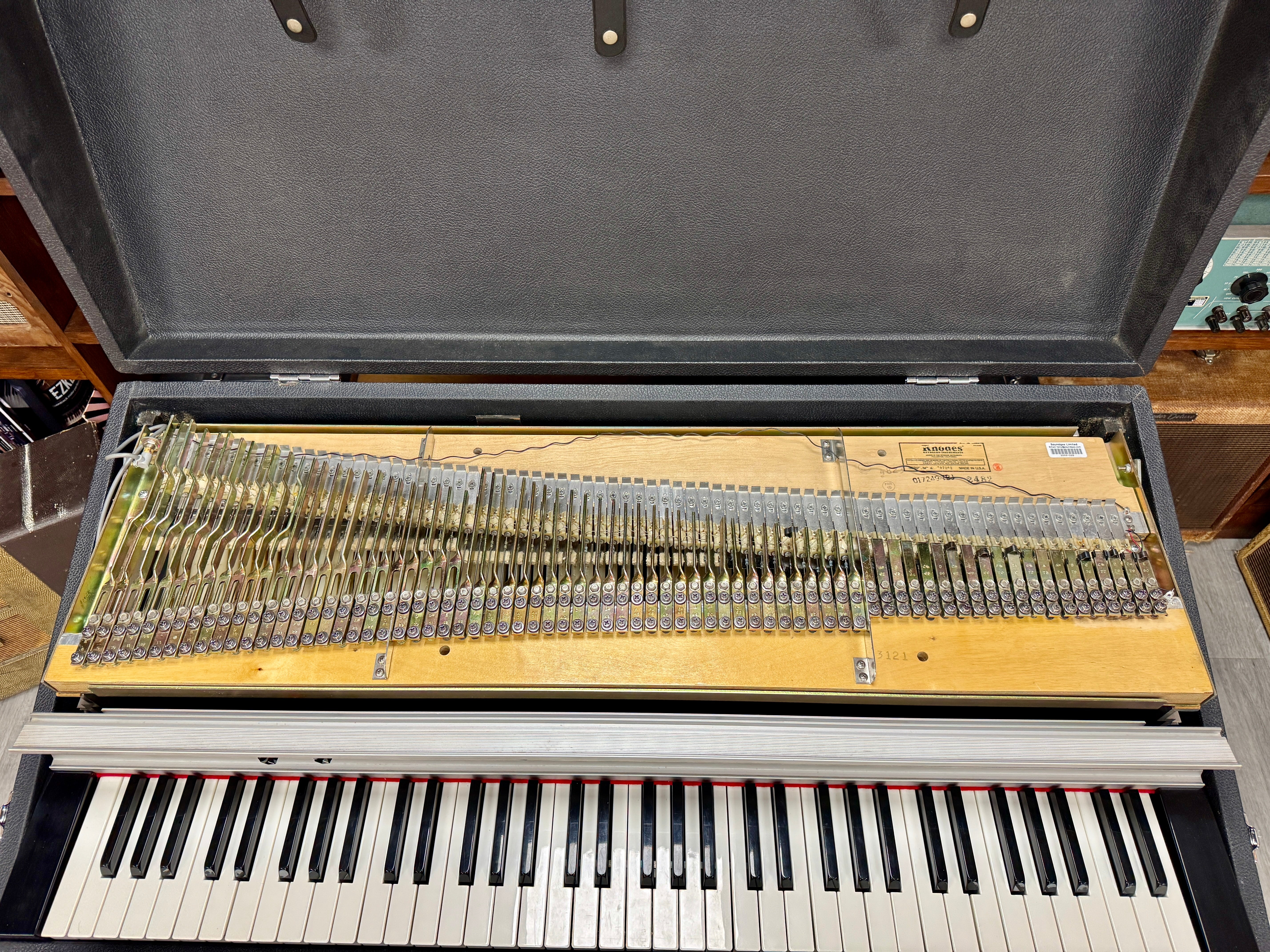 Piano keyboard inside an open case on a wooden floor.