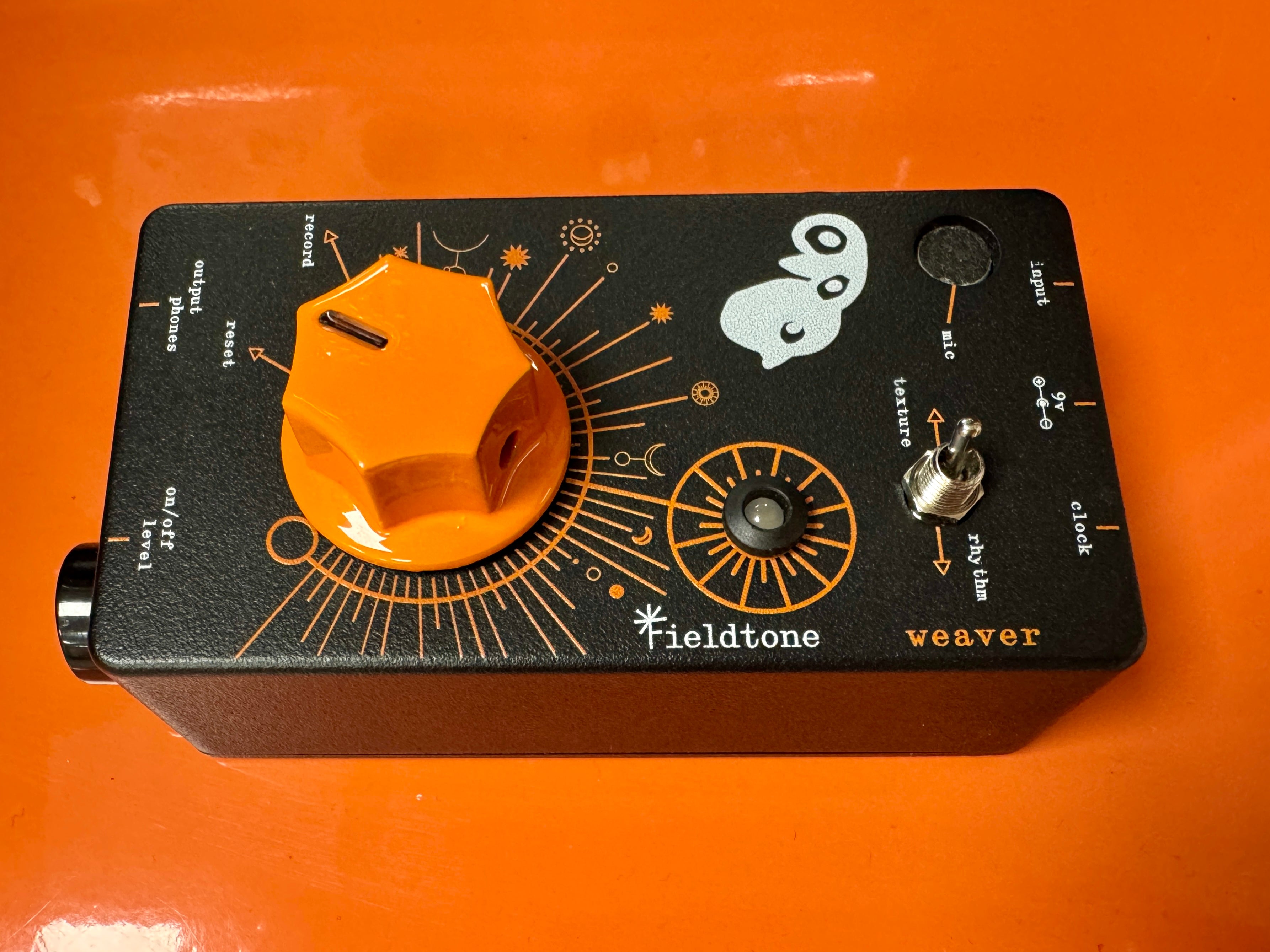 Guitar effects pedal with orange knob on a black background, featuring Fieldtone branding.