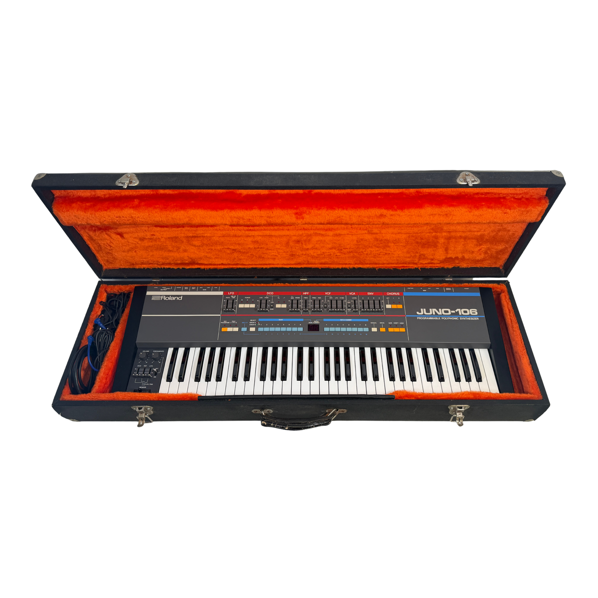 A vintage Juno-106 synthesizer keyboard inside an open black hard case with a bright orange interior, photographed against a plain white background.