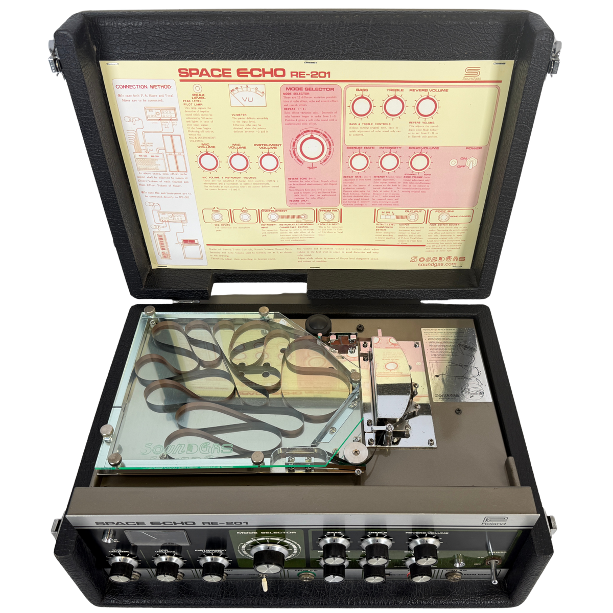 An open vintage Space Echo RE-201 sound reinforcement system in its black carrying case, showing the internal speaker assembly, control panel with knobs, and the instruction manual inside the lid.