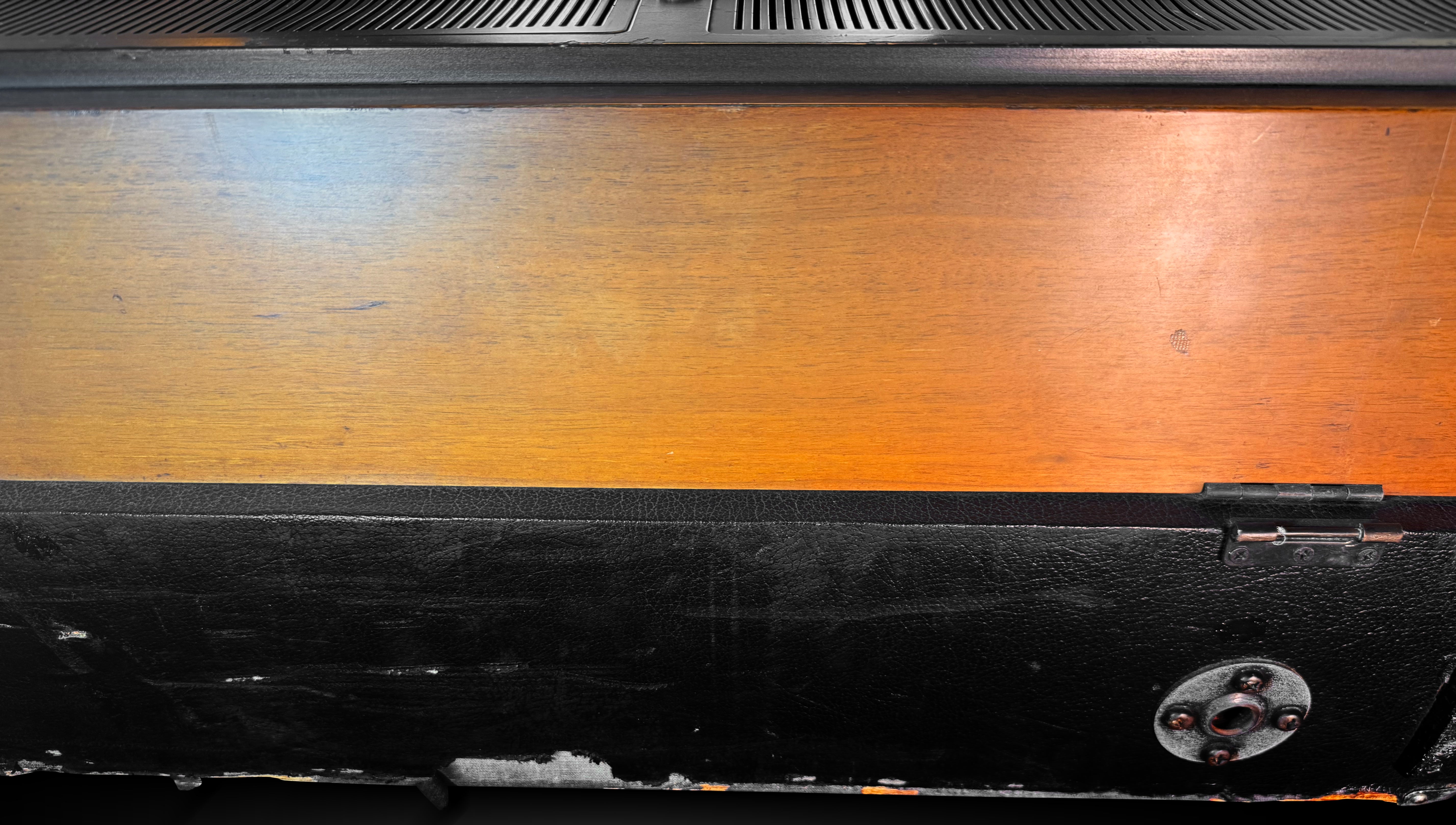 Close-up of a wooden surface with a black border and metal lock detail.